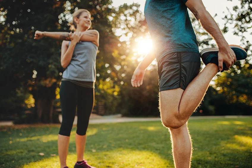 A man and woman are exercising in the park