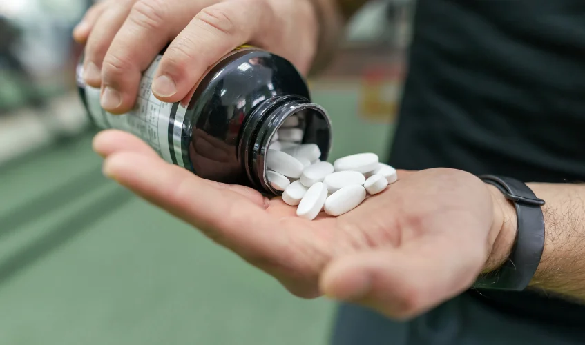 capsules, pills, gym background.