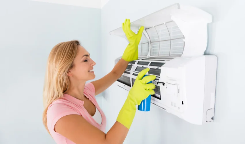 Happy Woman Cleaning The Air Conditioner
