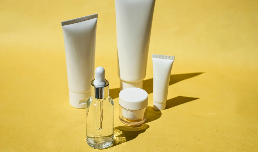 Serum Bottle, Cosmetic Tubes and Container on Yellow Background