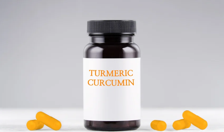 nutritional supplement turmeric curcumin bottle and capsules on gray