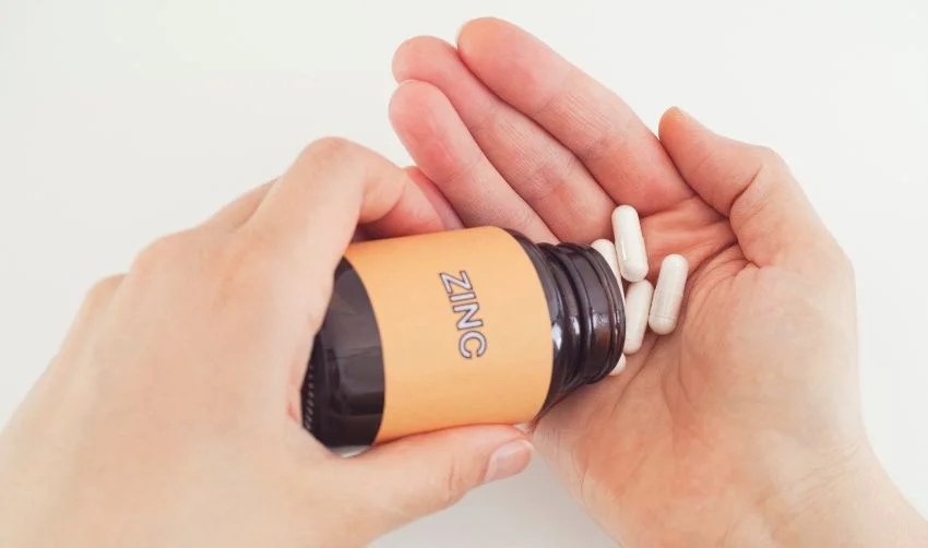 Person taking Zinc pills out of a bottle