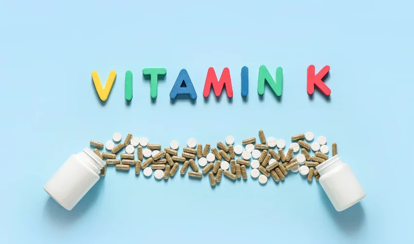 Composition with Word VITAMIN K and Pills on Color Background