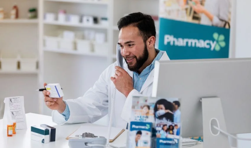 Male pharmacist uses pharmacy telephone
