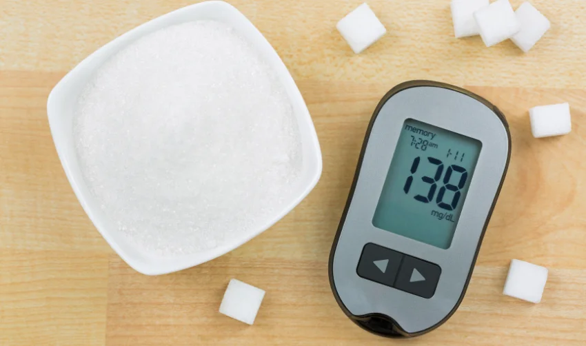 Blood Glucose meter device showing high blood sugar levels, next to sugar cubes