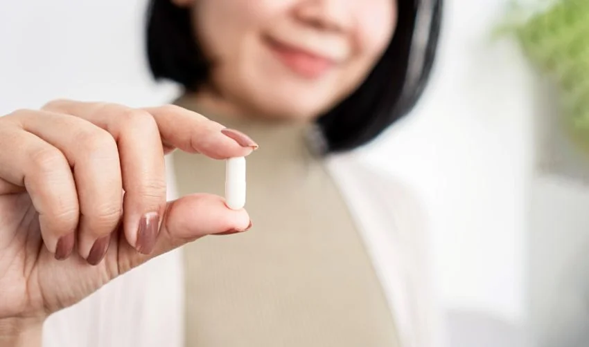 Asian woman holding a supplement pill